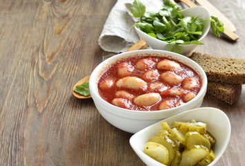 White beans in tomato sauce served with pickled cucumbers