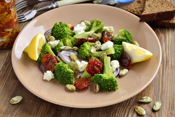 Salad with broccoli, dried tomatoes, feta, onions and pumpkin seeds