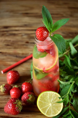 Lemonade with strawberry, lime, ice cubes and mint in a glass bottle