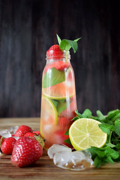 Lemonade with strawberry, lime, ice cubes and mint in a glass bottle