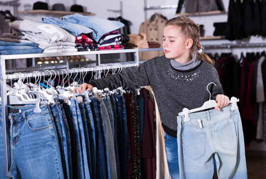 Teen girl choosing jeans in store