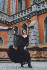 Young brunette girl in gothic style on a background architecture