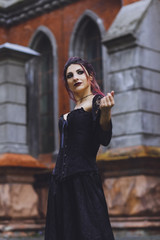 Young brunette girl in gothic style on a background architecture