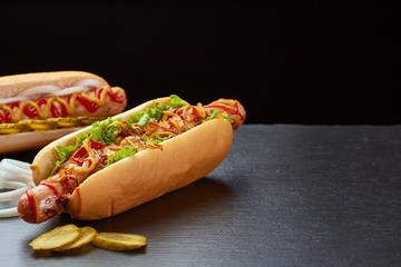 Two juicy hot dogs on dark slate background