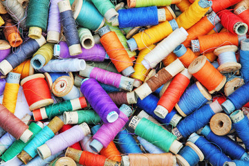 Heap of multicolored sewing threads in spools taken as background.