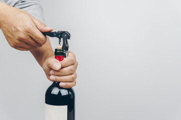 hand using a metal corkscrew to open the red wine bottle