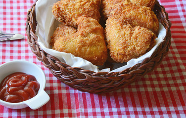 Fried chicken wings are heart-shaped in a basket with ketchup.