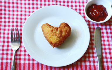 Fried chicken wings are heart-shaped in the dish and in the basket with ketchup.