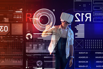 Amazing virtual reality. Emotional cheerful girl smiling and touching the round diagram on a transparent screen while wearing virtual reality glasses