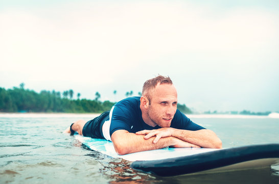 Man surfer rests lying on surfboard