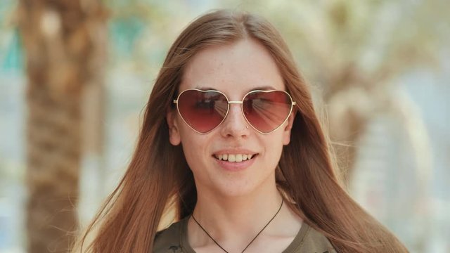 Girl in sunglasses on the background of Dubai streets and palms trees. Face close-up.