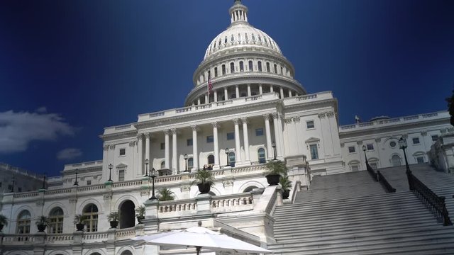 Steadicam motion looking up at the US Capitol dome and moving past the stairs.
