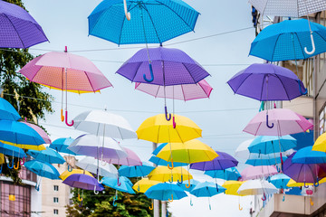 Installation of multicolored umbrellas on the street of a modern city_