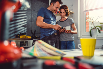 Couple using smart phone in kitchen during renovation