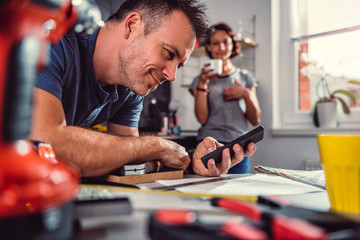 Men renovating kitchen and using smart phone