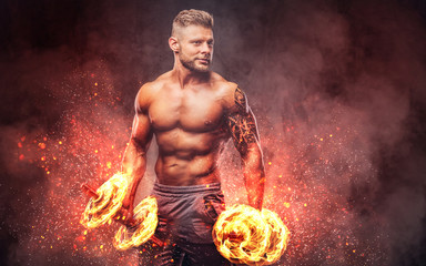Handsome shirtless tattooed bodybuilder with stylish haircut and beard, wearing sports shorts,...