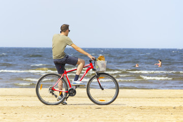 Fototapeta premium the man is sitting on a bicycle, the beach 