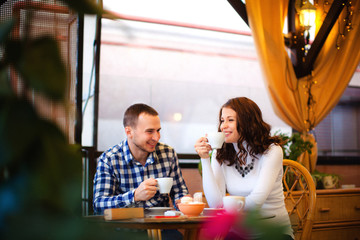 Pregnant woman and her husband sitting at cozy cafe terrace in the fall