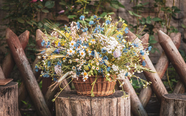 Wild flowers in a basket on a rustic background. Vintage scenery.