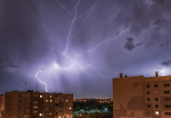 night city view under thunderstorm with strike of lightning.