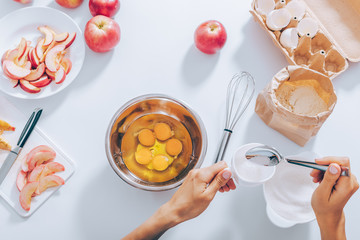 Woman's hands measuring cup of sugar to mix it with eggs