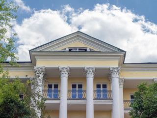 House with columns in the classical style against the blue sky with clouds. Count Orlov's summer house