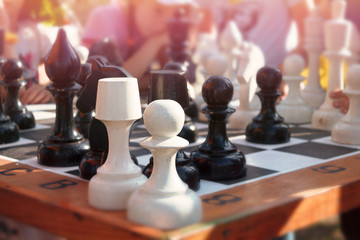 Big chess figures on a chess table in the street in summer