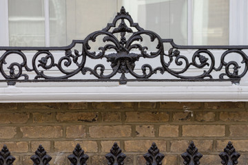 Ornamented metal framework on fencing outside houses in London. 