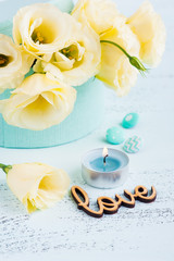 Yellow eustoma flowers, lit blue candle