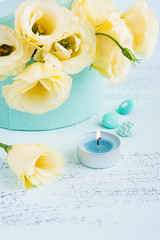 Yellow eustoma flowers, lit blue candle