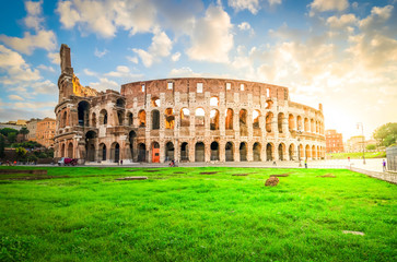 Fototapeta na wymiar ruins of antique Colosseum with grass lawn in sunise lights, Rome Italy, toned