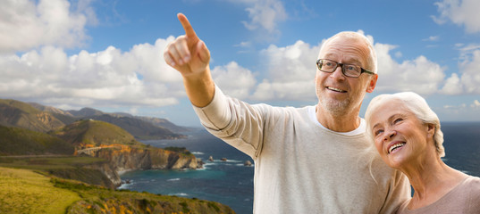 old age, tourism, travel and people concept - happy senior couple over bixby creek bridge on big sur coast of california background