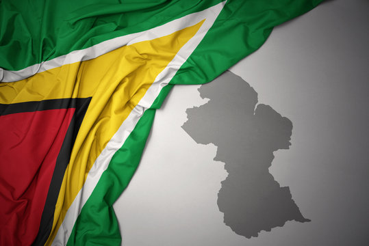 waving colorful national flag and map of guyana.