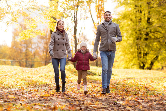 family, season and people concept - happy mother, father and little daughter walking at autumn park