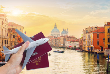Plane travel concept, hand holding passports with plane against Venice cityscape