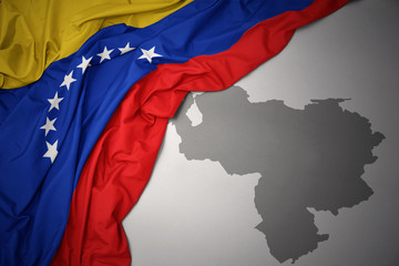 waving colorful national flag and map of venezuela.