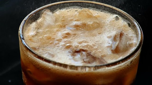 Cola with ice. Pouring Cola with Ice and bubbles in glass. Soda.