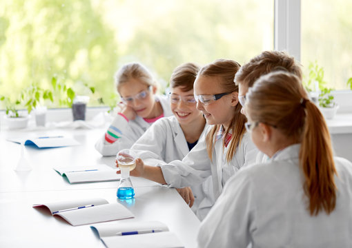 education, science, chemistry and children concept - kids or students with test tube making experiment at school laboratory