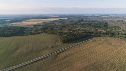 Flight above countryside green fields, forest, and village early spring, aerial panoramic view photo.