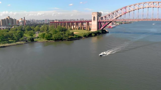 Boat in East River with the Hell Gate Bridge in the background. Camera follows boat downwards as it progresses.