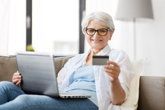 Technology, Online Shopping And People Concept - Happy Senior Woman In Glasses With Laptop Computer And Credit Or Bank Card At Home