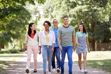 people, friendship and international concept - group of happy friends walking in park