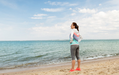 fitness, sport and healthy lifestyle concept - woman in sports clothes on beach