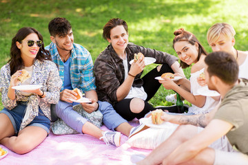 friendship, leisure and fast food concept - group of happy friends eating sandwiches or burgers at...