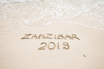 Zanzibar 2019 year description on light sand with waves