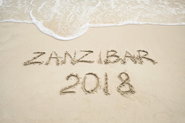 Fototapeta na wymiar Zanzibar 2018 year description on light sand with waves