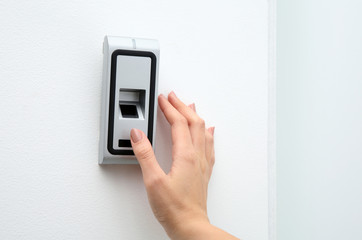 Young woman pressing fingerprint scanner on alarm system indoors