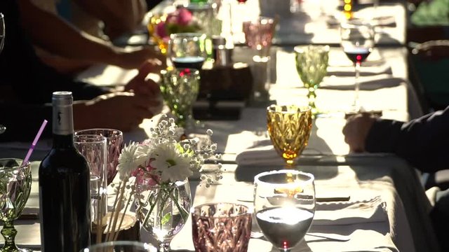 People at the table tasting wine. Clink glasses of red wine. On the table white tablecloth and utensils. Wine tasting.