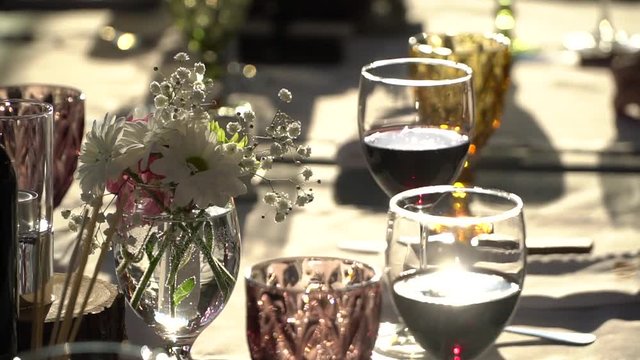 On the table are glasses of wine, flowers. Close-up shows glasses of wine illuminated by natural sunlight. Wine tasting.
