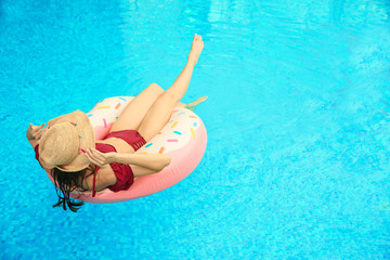 Beautiful young woman on inflatable ring in swimming pool